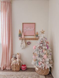 a christmas tree and other decorations in a child's room with pink drapes