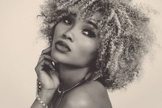 a black and white photo of a woman with curly hair wearing necklaces, looking off to the side