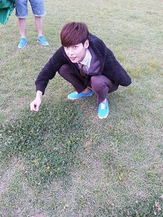 a young man kneeling down on top of a lush green field