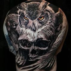 an owl tattoo on the back of a man's upper half - sleeved body