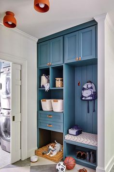 an organized laundry room with blue cabinets and baskets on the shelves, along with other items