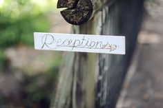 a close up of a sign on a fence with trees in the backgroud