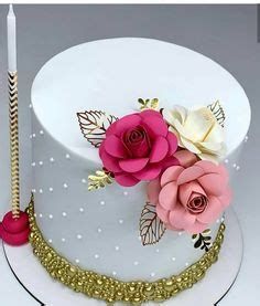 there is a white cake with pink flowers on it and a candle in the middle