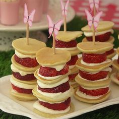 there are many pancakes with strawberries on them and some pink butterflies sticking out of them