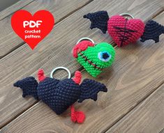 three crocheted monster key chains on a wooden table