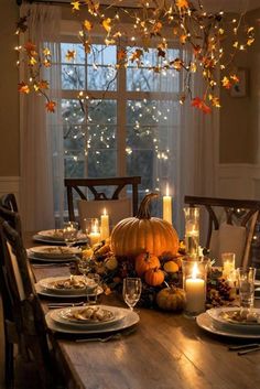 a dining room table with candles, plates and pumpkins on the table in front of a window