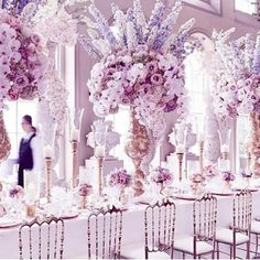 a man standing in front of a table with flowers on it and chairs around it