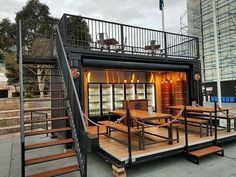 a house made out of shipping containers with stairs leading up to the second floor and windows