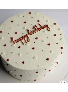 a white cake with red hearts and the words happy birthday on it's side