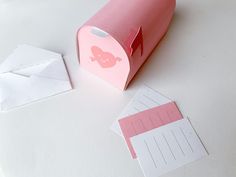 a roll of pink paper sitting on top of a table next to some envelopes