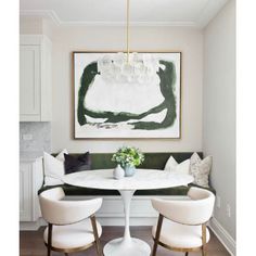 a dining room table with white chairs and a painting on the wall