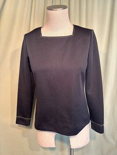 This is a sweet vintage top from the 70s.  Labeled My Latest Leslie Fay. No size tags. The bust measures 38", see measurements below. This classic top is made of black polyester. It has beige trim around the square neckline, along with double rows of beige top stitching. The same stitching trims the sleeve cuffs. It is a pullover top that zips down the back with a nylon zipper.    The top is in very good condition!  No damage or soil. Super cute!  If you have never worn vintage before, please measure yourself!! Vintage sizes run smaller than today's sizes, know your measurements before buying! Bust measured from side seam to side seam at the underarm: 18" for a 36" bust Waist measured from side seam to side seam at hem: 19" for a 38" hemline Shoulders: 14" Length measured from shoulder to Retro Long Sleeve Office Tops, Retro Fall Office Tops, Retro Black Tops For Work, Retro Fall Workwear Tops, Vintage Black Office Tops, Vintage Black Office Top, Beige Trim, 70s Tops, Vintage Blouses