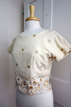 "White Wool with Gold and Silver Embroidery 5 covered button in back Lined Size Bust - 38\" Waist - 32\" Arm from Neck - 8.5\" Length - 18\" Condition - Excellent" Elegant Fitted Cotton Embroidered Top, Cream Short Sleeve Top For Wedding, Fitted Cream Blouse With Floral Embroidery, Fitted Cream Tops With Floral Embroidery, Fitted Wedding Tops With Gold Embroidery, Cream Fitted Cotton Blouse, Fitted Cream Cotton Blouse, Fitted Vintage Embroidered Top With Short Sleeves, Fitted Vintage Embroidered Short Sleeve Top