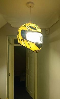 a yellow helmet hanging from the ceiling in a hallway with an open door to another room