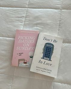 two books sitting on top of a bed next to each other in front of a white comforter