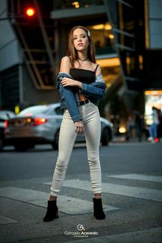 a beautiful young woman standing in the middle of a street