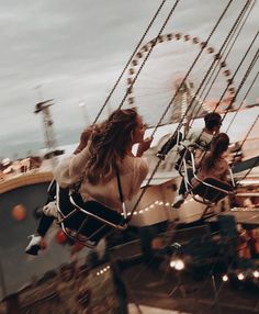 two people riding on a merry go round at an amusement park with ferris wheel in the background