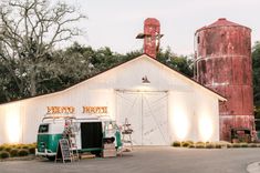 a green and white van parked in front of a barn next to a silo