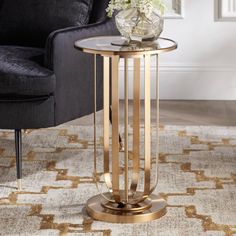 a living room with a black chair and a gold side table on top of a rug