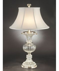 a glass lamp with a white shade on it's base and a silver finish