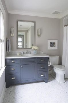 a white toilet sitting under a bathroom mirror next to a sink in a bath room