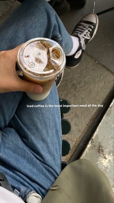 a person sitting down holding a cup of coffee in their hand with the caption iced coffee is the most important meal of the day