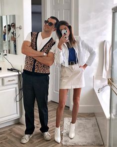 a man and woman taking a selfie in a bathroom with mirrors on the wall