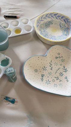 the table is covered with dishes and paintbrushes, including one heart - shaped dish