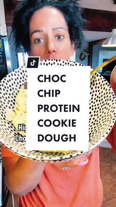 a woman holding up a sign with the words choc chip protein cookie dough on it