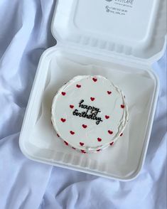 a white cake in a plastic container with red hearts on it and the words happy birthday