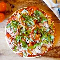 a pizza sitting on top of a wooden cutting board next to some tomatoes and cheese