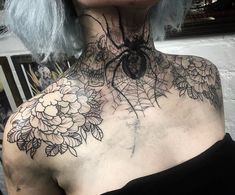 a woman with grey hair has a spider web tattoo on her chest