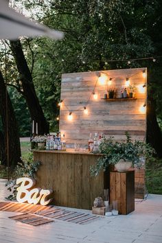 an outdoor bar set up with lights and plants