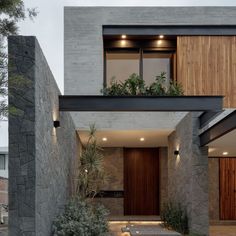 the entrance to a modern house with stone walls and plants on the windows sill