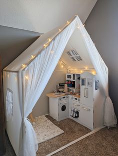 a white tent with lights hanging from it's ceiling in the corner of a room