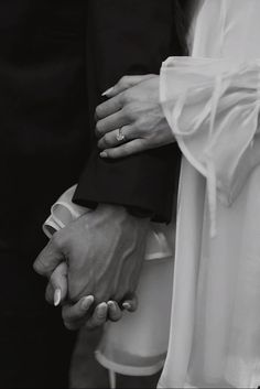 black and white photograph of two people holding each other's hands with their wedding rings