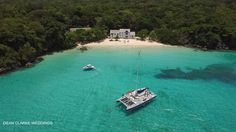 an aerial view of a boat in the water near a beach with trees and a house