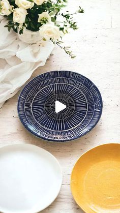 three plates sitting on top of a table next to a vase with flowers in it