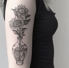 a black and white photo of a woman with a sunflower tattoo on her arm