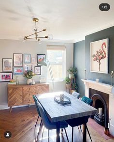 a dining room table and chairs in front of a fireplace with pictures on the wall