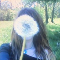 a woman holding a dandelion up to her face