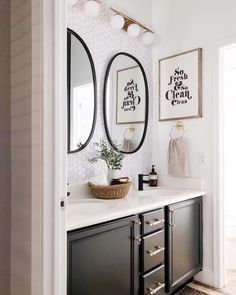 a bathroom with black and white decor on the walls, two round mirrors above the sink