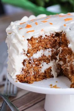 a carrot cake with white frosting and orange sprinkles on a plate