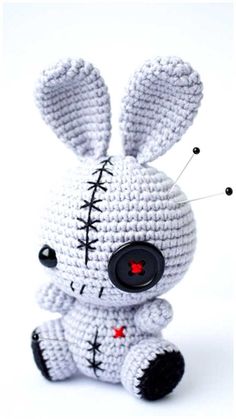 a white crocheted stuffed animal with black stitches on it's face and eyes