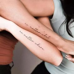 two women with matching tattoos holding each other's arms, both have words written on them