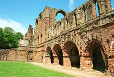 an old brick building with arches and doorways in the middle of a grassy area