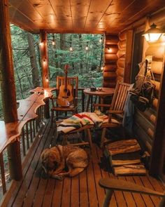 a dog laying on top of a wooden porch next to a rocking chair and table