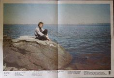 a man sitting on top of a rock next to the ocean