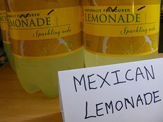 two bottles of lemonade sitting on top of a table next to a sign that says mexican lemonade