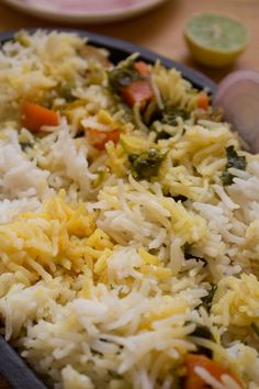 rice and vegetables are mixed together in a dish on a table next to plates with utensils